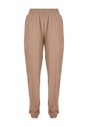 Gros plan sur une main dans la poche d'un pantalon décontracté beige avec une ceinture élastique et le logo "aimn" sur la cuisse.