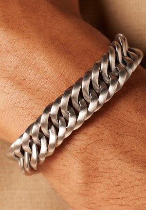 Silberner Metallarmband mit ineinandergreifenden Gliedern, mit einer glatten, polierten Textur, die am Handgelenk auf einem hautfarbenen Hintergrund getragen wird.