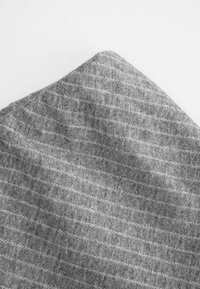 Szara tkanina z teksturowanym wzorem, z delikatnym szkockim wzorem. Materiał wydaje się miękki, z różnymi odcieniami szarości w całej powierzchni.