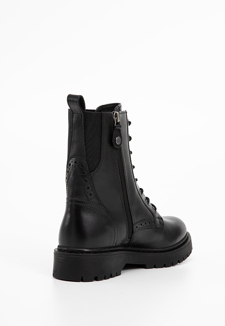 Schwarze Lederstiefelette mit Seitenreißverschluss, strukturiertem Finish, Schnürung vorne und Brogue-Details. Robuste Gummisohle für guten Halt.
