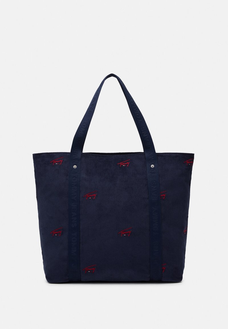 Sac fourre-tout en velours côtelé bleu marine avec deux anses et petits logos rouges brodés dispersés sur le tissu extérieur.
