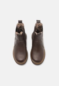 Bottines en cuir marron avec une finition lisse, doublure en fourrure, panneaux latéraux élastiques et semelle en caoutchouc. Conçues pour la chaleur et le confort.