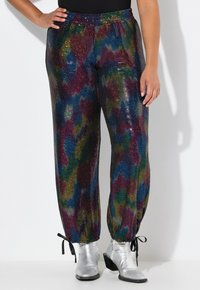Pantalones de lentejuelas multicolores con un ajuste holgado y cinturilla elástica. Presentan puños fruncidos con lazos, textura brillante y patrones vibrantes.