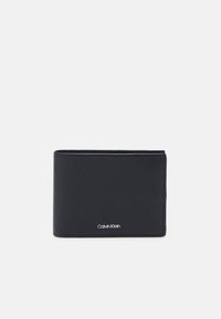 Must mustra nahkrahakott koos tekstureeritud pinnaga, kaheosaline disain ja nähtav Calvin Klein logo alumisel esiosas.