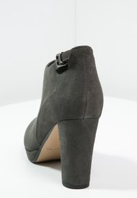 Grå mocka högklackad stövel med rund tå, justerbar spänndetalj och en texturerad yta. Klackar cirka 10 cm höga.