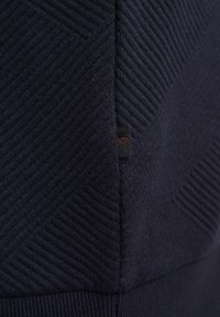 Felpa blu navy con un design testurizzato e a motivo con righe diagonali. Include un piccolo etichetta con il logo sul lato.