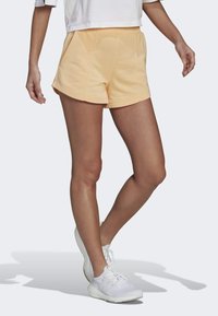 Shorts i mjuk persikofärgad tyg med elastisk midja, med en avslappnad passform, sidofickor och en slät textur. Matchas med vita sneakers.