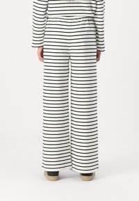 White pants with black horizontal stripes, wide leg design, elastic waistband, and a smooth cotton texture. Back view shown.