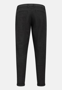 Pantalon de costume gris anthracite à jambes fuselées, avec poches arrière passepoilées et ourlets retroussés sur fond uni.