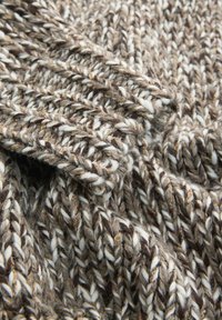 Pruun ja valge kootud kangas, millel on paks ja tekstureeritud muster. Lõng näitab värvitoonide varieeruvust, luues hubase välimuse.