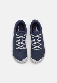 Zapatos azul marino con un upper texturizado, cordones blancos y una suela de goma gris con patrones angulares. Logo de la marca visible en el lateral.