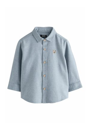Camicia azzurro chiaro in morbido tessuto con maniche lunghe, caratterizzata da un piccolo bordo ricamato a forma di orso e bottoni in legno.