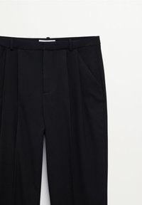 Pantalon noir ajusté avec un devant plat, deux poches latérales, des plis et une texture lisse. Comprend une ceinture avec passants pour ceinture.