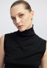 Maglione senza maniche nero a collo alto con finitura testurizzata, caratterizzato da un colletto ondulato e dettagli in argento sparsi.