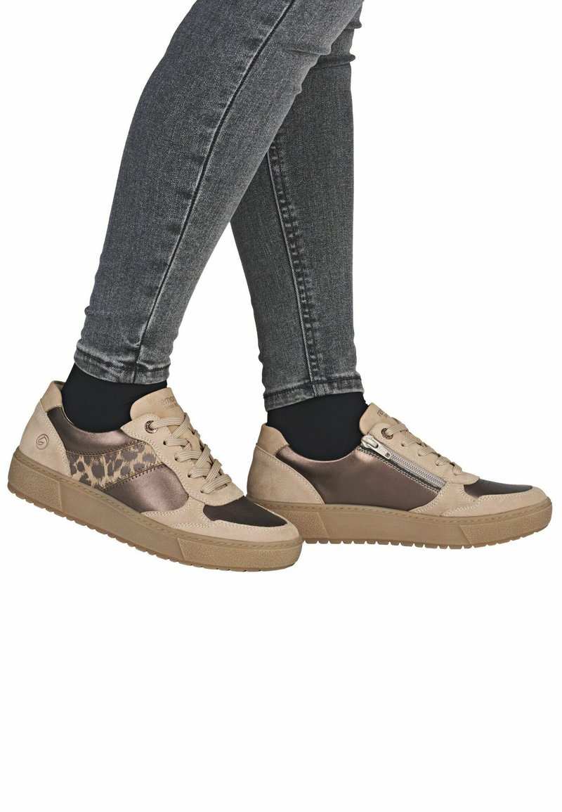 Baskets beiges et marron avec tige en cuir et textile, présentant un accent à imprimé léopard et une fermeture éclair sur le côté. Semelle en caoutchouc texturée.