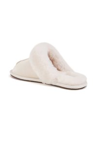 Witte schapenvachten pantoffels met een zachte, donzige voering, ronde open teen en platte zool, met een eenvoudig, minimalistisch ontwerp.