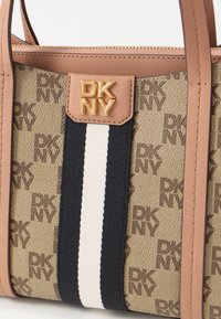 Tote bag with DKNY monogram canvas, beige with brown logo, features navy and white stripes, tan accent trim, and gold logo hardware.