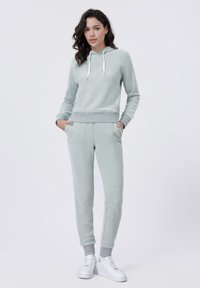 Lichtgroene fleece hoodie met zakken aan de voorkant, geribbelde zoom en een trekkoord. Gecombineerd met bijpassende joggers met enkelmanchetten en zakken.