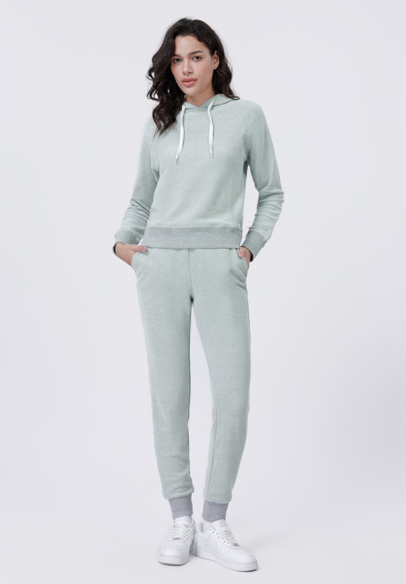 Lichtgroene fleece hoodie met zakken aan de voorkant, geribbelde zoom en een trekkoord. Gecombineerd met bijpassende joggers met enkelmanchetten en zakken.