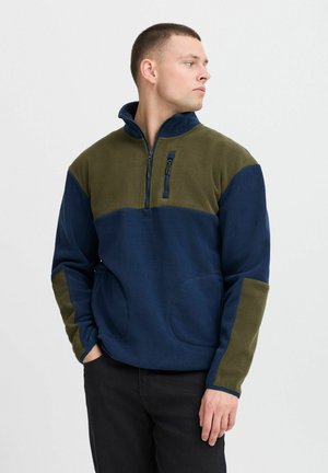Fleece pullover in navy and olive, half-zip front, side pockets, and contrasting sleeve panels. Soft texture, casual design.