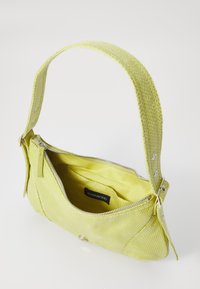 Sac à main texturé vert clair avec fermeture zippée, courte bandoulière et doublure intérieure lisse. Se distingue par des accents en métal argenté.