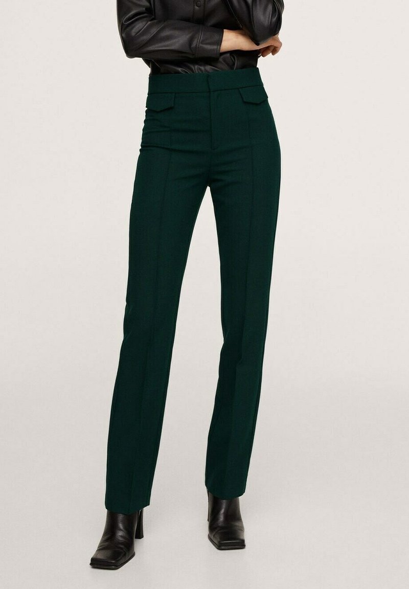 Pantalons ajustés vert foncé à taille haute, avec deux poches avant, des lignes verticales et une coupe slim, assortis à des bottes noires à talons.