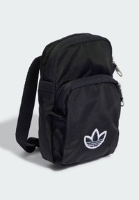 Svart nylonryggsäck med en texturerad yta, med en framficka och vit broderad logotyp. Justerbar rem för enkel bärning.