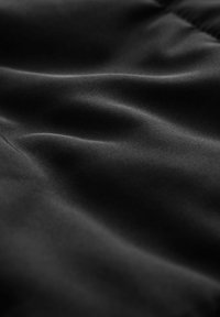 Melna satīna audums ar gludu tekstūru, izrādot mīkstas viļņošanās un nevainojamu spīdumu, bez jebkādām rakstu vai aparatūras akcentiem.