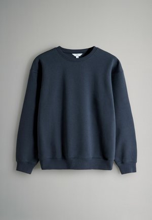 Mörkblå sweatshirt med rund halsringning, långa ärmar, ribbade muddar och fåll, tillverkad av ett mjukt tyg med en slät textur.