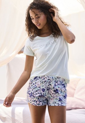 Light green short-sleeve t-shirt with "DREAMS" text, paired with multicolored floral print shorts featuring a drawstring waist.