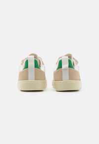 Sneaker bianchi e beige con accenti verdi. Superiori in camoscio e materiale sintetico, suola piatta in gomma e collo imbottito con linguetta sul tallone per un facile indossamento.