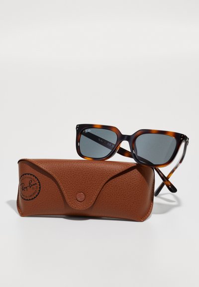 Слънчеви очила Ray-Ban с черупка в цветен модел, почиващи върху кафяв текстуриран кожен калъф с копче за закопчаване и лого.
