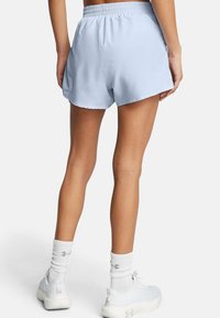Hellblaue Sportshorts mit elastischem Bund, seitlichen Mesh-Akzenten und einer lockeren Passform, kombiniert mit weißen Socken und Schuhen.