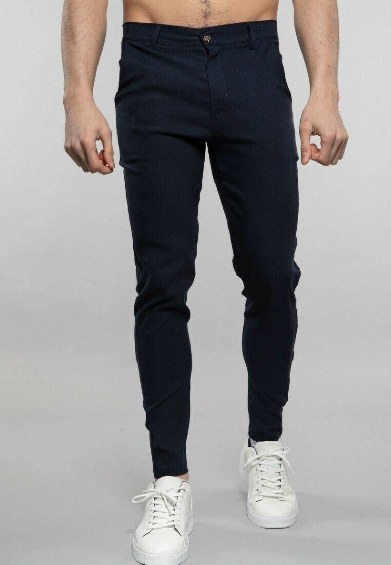 Pantalons ajustés bleu marine en mélange de coton. Dotés d'une fermeture éclair, d'un bouton unique et de poches avant. Associés à des baskets blanches.