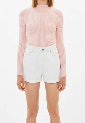 Light pink ribbed long-sleeve sweater paired with white denim shorts with rolled hems, featuring front pockets and a metal fastening.