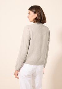Giacca bomber grigia chiara realizzata in tessuto texturizzato, con polsini e vita a coste, dal design semplice e senza motivi visibili.