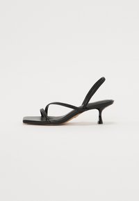 Sandalo nero con cinturini, punta quadrata, cinturini sottili e tacco corto a blocco. Superficie in pelle liscia e design minimalista.