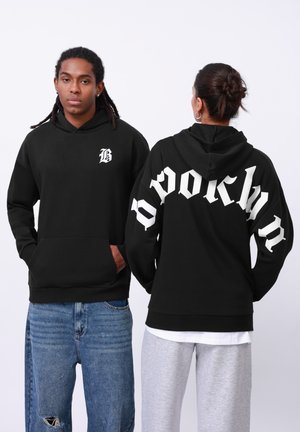 Black hooded sweatshirt featuring a small white "B" on the front and "BROOKLYN" in large white font on the back. Cotton blend fabric.