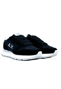 Scarpe sportive nere con tomaia in suede e mesh, suola in gomma bianca, lacci piatti e un logo visibile sul lato e sulla linguetta.