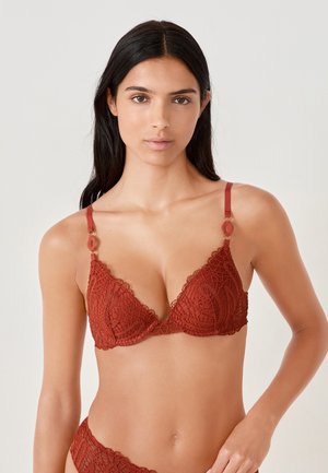 Bordeaux kant bralette met een driehoekige vorm, gegolfde randen en decoratieve metalen details op de bandjes. Subtiel bloemmotief overal.