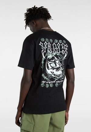 Black cotton t-shirt featuring a large graphic on the back with a skull, floral accents, and text in white and green. Crew neck design.