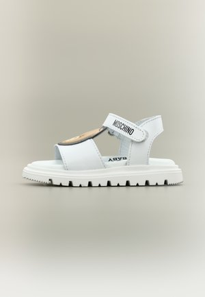 Sandalino bianco per toddler con cinturino in Velcro etichettato "Moschino", suola robusta e dettaglio con faccia di orsetto sul cinturino frontale.