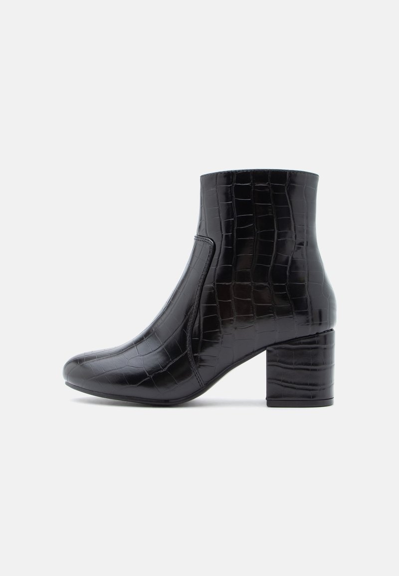 Bottine noire avec texture crocodile, talon bloc, bout arrondi et finition lisse vue de profil sur fond blanc.