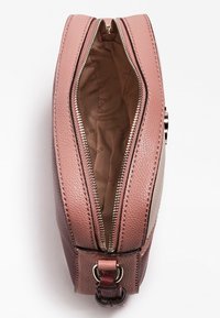 Vaaleanpunainen nahkalaukku vetoketjulla, jossa on sileä pinta ja beige paneeli. Sisäpuolella on vaaleanbeige vuori, jossa toistuvia logoja.