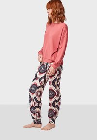 Sudadera rosa de manga larga combinada con pantalones blancos que presentan un patrón multicolor de ojos y soles. Tela suave con puños elásticos.