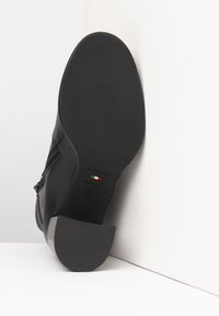 Bottines en cuir noir avec une semelle en caoutchouc plate, détail de fermeture éclair sur le côté et marquage sur le talon. Fabriqué en Italie, taille 37.