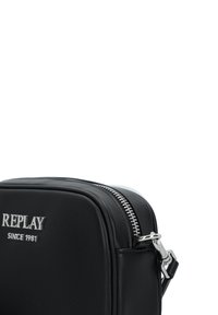 Svart läderväska med silverfärgad dragkedjestängning, med präglad "REPLAY"-logotyp och elegant rektangulär design. Slät textur och minimalistisk stil.