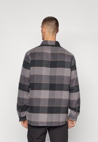 Grå og svart rutete flanellskjorte med lange ermer, krage og knappeærmer; har et teksturert stoff og en rett hem.