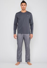 Chemise grise à manches longues associée à un pantalon de pyjama à motifs dans des tons de gris, présentant un design géométrique et un ajustement confortable.