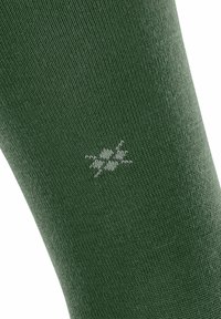 Nahaufnahme einer strukturierten grünen Socke mit einem kleinen weißen Bienenmuster, das in den Stoff eingestrickt ist, und das den Stil und die Details der Socke betont.